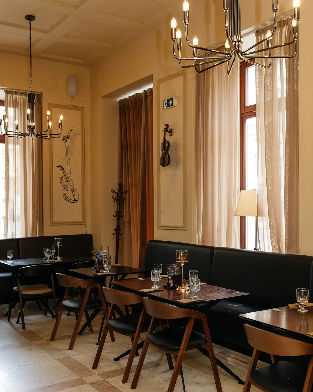 Interior of Restaurace A. Dvořák: chandeliers, a violin on the wall and laid tables