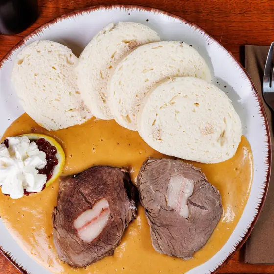 Svíčková in cream sauce with bread dumplings, cranberries and whipped cream