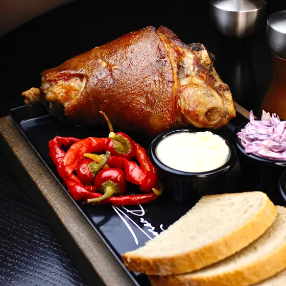 Roast pork knuckle with chilli peppers, sauces and bread
