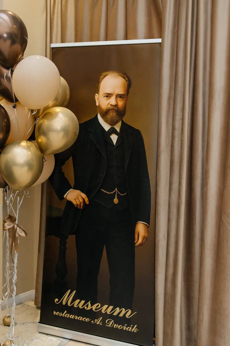 A roll-up banner reading Museum restaurace A. Dvořák, with a colourised portrait of the composer