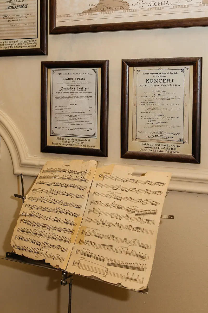 Framed historical concert posters and an old score on a music stand