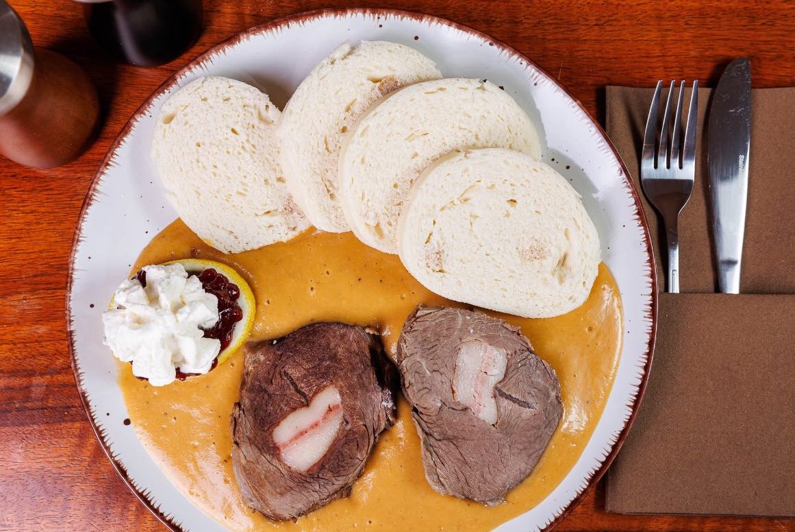 Traditional Czech food in Prague – svíčková na smetaně with bread dumplings and cranberries.