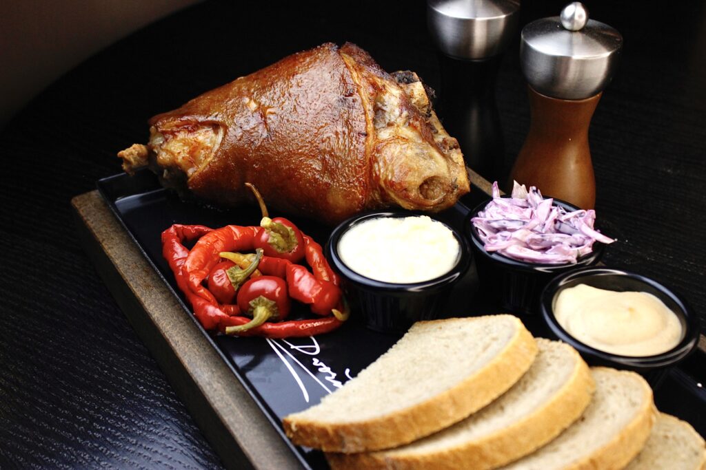 Tradiční české jídlo – pečené vepřové koleno se zelím, křenem a chlebem v restauraci A. Dvořák Praha.