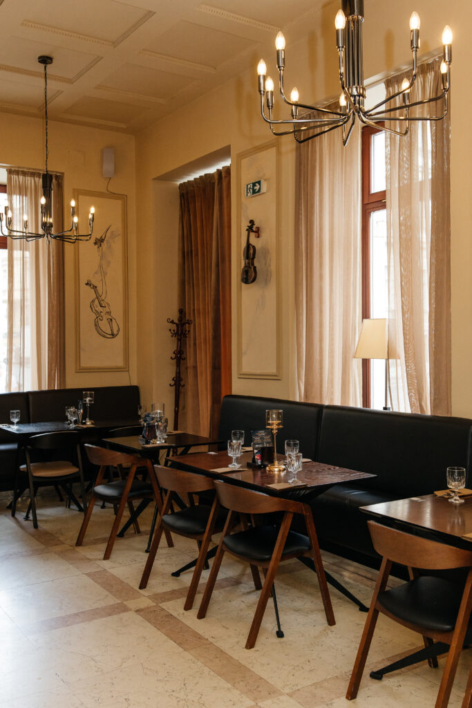 Interiér pivovarské restaurace A. Dvořák v Praze — elegantní sál s dřevěným nábytkem a hudební výzdobou na stěnách.