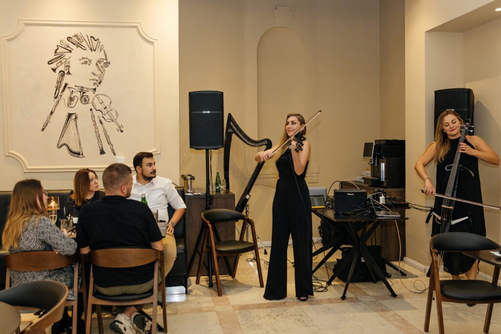Hudební vystoupení houslistky a violoncellistky před hosty během oficiálního otevření pivovarské restaurace a muzea A. Dvořák Praha.